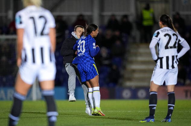 Sam Kerr of Chelsea shoulder barges over a pitch invader who ran on trying to take selfies during the UEFA Women s Champions League match between Chelsea Women and Juventus at the Kingsmeadow Stadium, Kingston, England on 8 December 2021. Copyright: xAndyxRowlandx PMI-4604-0001