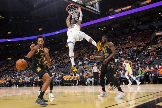 December 18, 2021, Toronto, ON, Canada: Golden State Warriors Jonathan Kuminga hangs from the hoop after scoring as Toronto Raptors Scottie Barnes (left) and Precious Achiuwa look on during second half NBA, Basketball Herren, USA basketball action in Toronto on Saturday, December 18, 2021. Canada News - December 18, 2021  - ZUMAc35_ 20211218_zaf_c35_100 Copyright: xChrisxYoungx