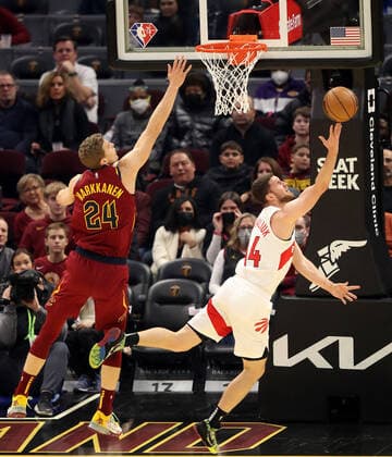 Toronto Raptors JSvi Mykhailiuk (14) scores past Cleveland Cavaliers Lauri Markkanen (24) at Rocket Mortgage FieldHouse in Cleveland, Ohio on Sunday, December 26, 2021.  CLE20211226108 AARONxJOSEFCZYK