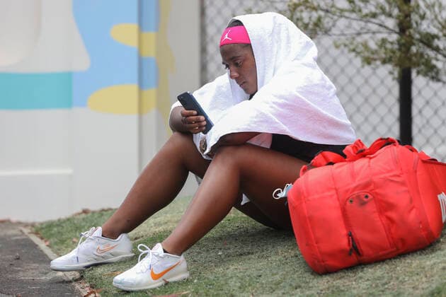 Hailey Baptiste USA sits crying on the grass with towel over her head and texts on her cell phone after losing the match Emotion Copyright: xJuergenxHasenkopfx