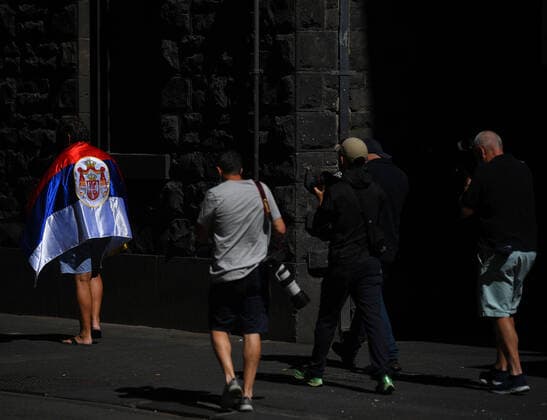 Tennis, Australian Open, Novak Djokovic auf dem zur Anhörung vor Gericht in Melbourne TENNIS NOVAK DJOKOVIC VISA, Members of the media take photographs of a supporter of Novak Djokovic wearing a Serbian flag outside Djokovic s lawyers office in Melbourne, Sunday, January 16, 2022. Novak Djokovic still faces uncertainty as to whether he can compete in the Australian Open, despite being announced in the tournament draw. ( NO ARCHIVING, EDITORIAL USE ONLY, NO USE IN BOOKS WITHOUT CONSENT MELBOURNE VIC AUSTRALIA  Copyright: xJAMESxROSSx 0147807413st
