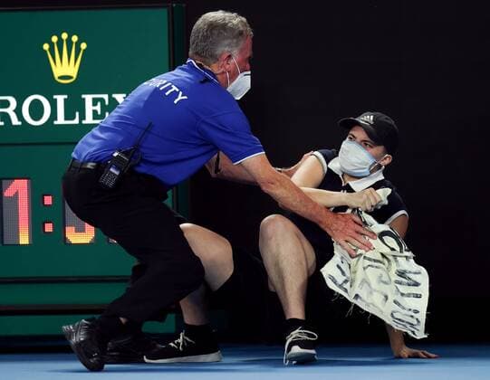 Mandatory Credit: Photo by Ella Ling Shutterstock (12778014bf) A protester is tackled by security and police during the Men s Singles final Australian Open, Day Fourteen, Tennis, Melbourne Park, Melbourne, Australia - 30 Jan 2022 Australian Open, Day Fourteen, Tennis, Melbourne Park, Melbourne, Australia - 30 Jan 2022 Copyright: xEllaxLing Shutterstockx 12778014bf