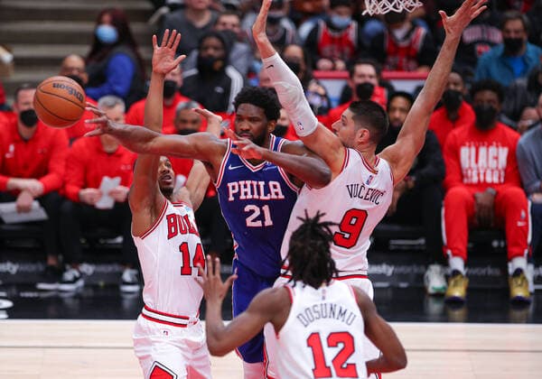 CHICAGO, IL - FEBRUARY 06: Philadelphia 76ers Center Joel Embiid (21) passes the ball while being double teamed by Chicago Bulls Guard Malcolm Hill (14) and Chicago Bulls Center Nikola Vucevic (9) during a NBA, Basketball Herren, USA game between the Philadelphia 76ers and the Chicago Bulls on February 6, 2022 at the United Center in Chicago, IL. (Photo by Melissa Tamez Icon Sportswire) NBA: FEB 06 76ers at Bulls Icon22020630
