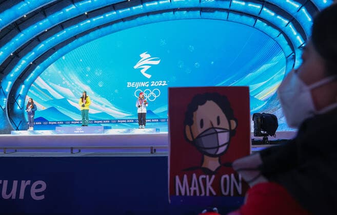 ZHANGJIAKOU, CHINA - FEBRUARY 7, 2022: A volunteer carries a sign to give visual signals allowing the medallists to take off their masks during the women s moguls victory ceremony at the Medal Plaza as part of the 2022 Winter Olympic Games, Olympische Spiele, Olympia, OS Sergei Bobylev TASS  TS121C9C