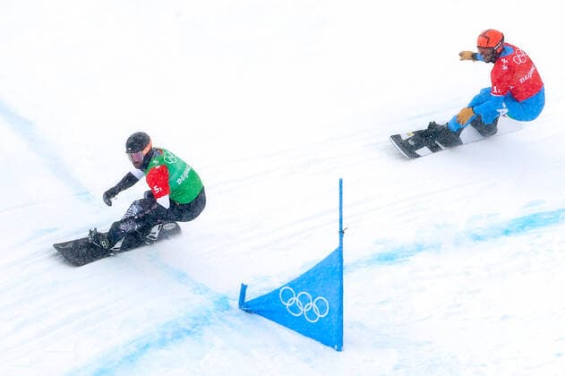 ZHANGJIAKOU, CHINA - FEBRUARY 12, 2022: Nick Baumgartner (L) of the USA and Omar Visintin of Italy compete in a mixed team snowboard cross semifinal at the 2022 Winter Olympic Games, Olympische Spiele, Olympia, OS at Genting Snow Park. Stanislav Krasilnikov TASS  TS12294B