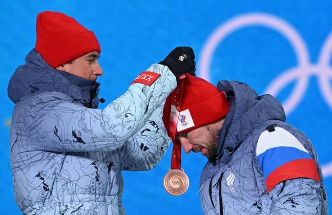 BEIJING 2022, Biathlon, 4x7,5km Staffel M?nner, Siegerehrung China Olympics 2022 Medal Ceremony 8116938 16.02.2022 Bronze medalist Russian Olympic Committee s Said Karimulla Khalili helps his teammate Alexander Loginov to put on his medal during an award ceremony for the biathlon men s 4x7.5 km relay event during the Beijing 2022 Winter Olympic Games, Olympische Spiele, Olympia, OS at the Medals Plaza in Zhangjiakou, China. Alexey Filippov Sputnik Beijing China  Copyright: xAlexeyxFilippovx