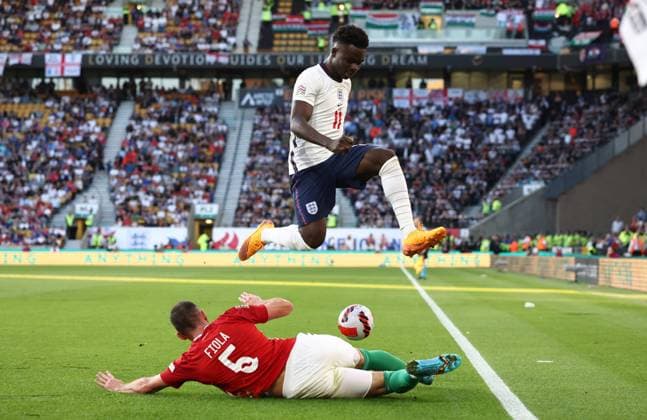 Wolverhampton, England, 14th June 2022. Bukayo Saka of England jumps over Attila Fiola of Hungary during the UEFA Nations League match at Molineux, Wolverhampton. Picture credit should read: Darren Staples Sportimage EDITORIAL USE ONLY. No use with unauthorised audio, video, data, fixture lists, club league logos or live services. Online in-match use limited to 120 images, no video emulation. No use in betting, games or single club league player publications. SPI-1734-0053