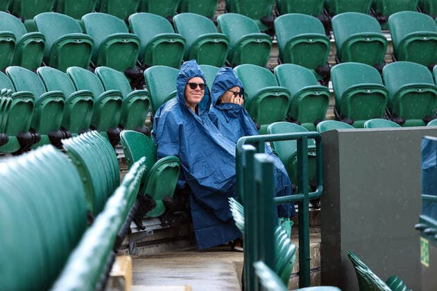 Tennis Wimbledon Tag 1 27. Juni 2022 Tennis Wimbledon Tag 1 Zwei Zuschauer sitzen in Regenmänteln und warten auf die Wiederaufnahme des Spiels Foto Simon Stacpoole Offside London UK  Copyright: xSimonxStacpoolexOffside
