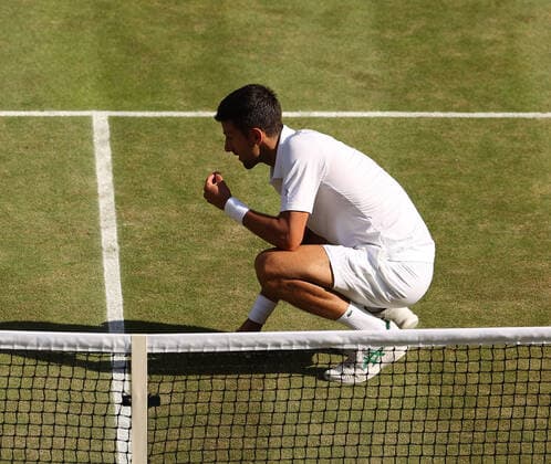 10th July 2022, All England Lawn Tennis and Croquet Club, London, England; Wimbledon Tennis tournament, mens singles final; Novak Djokovic (SRB) eating grass from centre court in celebration after defeating Nick Kyrgios (AUS)  ActionPlus12407301 JohnxPatrickxFletcher