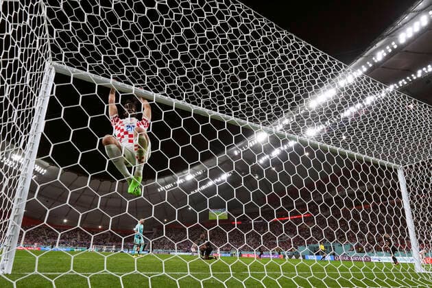 (221127) -- DOHA, Nov. 27, 2022 -- Josko Gvardiol (Top) of Croatia hangs off the crossbar during the Group F match between Croatia and Canada at the 2022 FIFA World Cup, WM, Weltmeisterschaft, Fussball at Khalifa International Stadium in Doha, Qatar, Nov. 27, 2022. ) (SP)QATAR-DOHA-2022 WORLD CUP-GROUP F-CRO VS CAN MengxDingbo 
