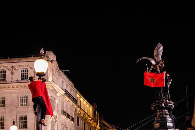 December 10, 2022, London, United Kingdom: A Morocco football supporter seen hanging a Moroccan flag on a lamp post at Piccadilly Circus to celebrate the winning over Portugal in 2022 FIFA World Cup, WM, Weltmeisterschaft, Fussball Moroccan, other North African and Middle-Eastern who reside in London celebrate in the city of London after Morocco beats Portugal in 2022 FIFA World Cup quarter-final. Morocco is the first African country breaking into semi-final in World Cup in history. London United Kingdom - ZUMAs197 20221210_zaa_s197_311 Copyright: xHestherxNgx