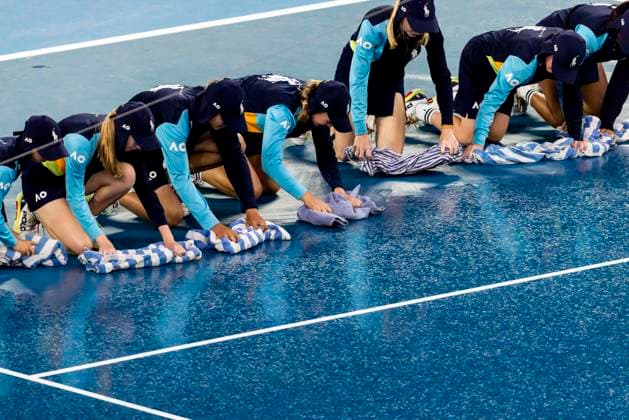 MELBOURNE, VIC - JANUARY 24: Ballkids and other tennis officials mop up after rain interrupted play during the Quarterfinals of the 2023 Australian Open on January 24 2023, at Melbourne Park in Melbourne, Australia. (Photo by Jason Heidrich Icon Sportswire) TENNIS: JAN 24 Australian Open Icon230124006