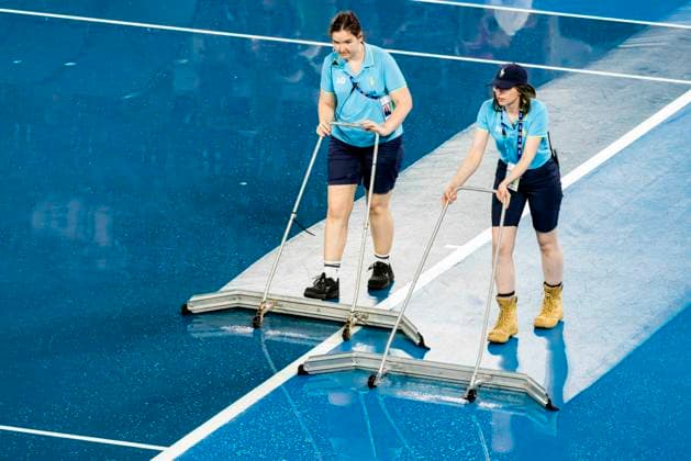 MELBOURNE, VIC - JANUARY 24: Ballkids and other tennis officials mop up after rain interrupted play during the Quarterfinals of the 2023 Australian Open on January 24 2023, at Melbourne Park in Melbourne, Australia. (Photo by Jason Heidrich Icon Sportswire) TENNIS: JAN 24 Australian Open Icon230124007