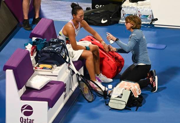 (230215) -- DOHA, Feb. 15, 2023 -- Zheng Qinwen (L) of China receives medical treatment during the singles round of 32 match against Maria Sakkari of Greece at WTA500 Qatar Open 2023 in Doha, Qatar, Feb. 14, 2023. (Photo by Xinhua) (SP)QATAR-DOHA-TENNIS WTA, Tennis Damen 500-DAY 2 Nikku 