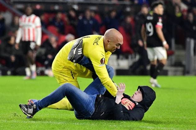 EINDHOVEN - A PSV supporter of PSV on the pitch with goalkeeper Marko Dmitrovic of Sevilla during the UEFA Europa league play-off match between PSV Eindhoven and Sevilla FC at Phillips stadium on February 23, 2023 in Eindhoven, Netherlands. ANP OLAF KRAAK PSV Eindhoven v Sevilla FC: Knockout Round Play-Off Leg Two - UEFA Europa League 2022 2023 xVIxANPxSportx xxANPxIVx 463455563 originalFilename: 463455563.jpg