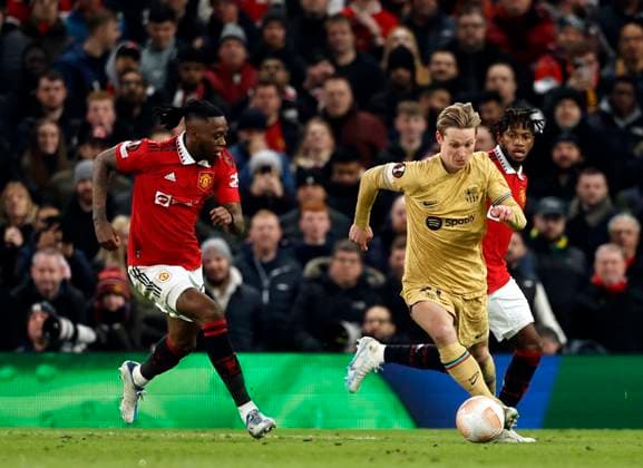 Football - 2022 2023 UEFA Europa League - Play-Off - Second Leg - Manchester United, ManU vs Barcelona - Old Trafford - Thursday 23rd February 2023 Frenkie de Jong of Barcelona breaks through midfield with Aaron Wan-Bissaka of Manchester United in pursuit, at Old Trafford. 