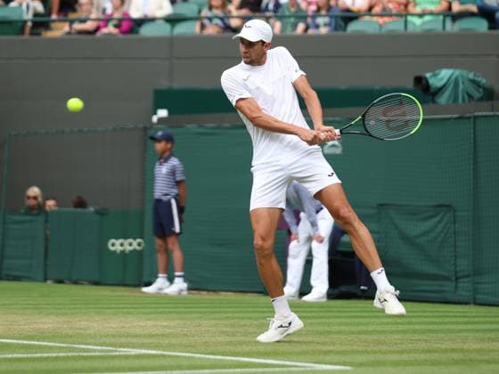 Columbia s Daniel Elah Galan plays a backhand in his match against Italy s Jannik Sinner on day seven of the 2023 Wimbledon championships in London on Sunday, July 9, 2023.  LON2023070913 HUGOxPHILPOTT