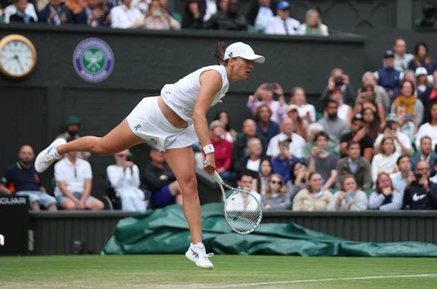 Poland s Iga Swiatek serves in her match against Switzerland s Belinda Bencic on day seven of the 2023 Wimbledon championships in London on Sunday, July 09, 2023.  LON2023070974 HUGOxPHILPOTT