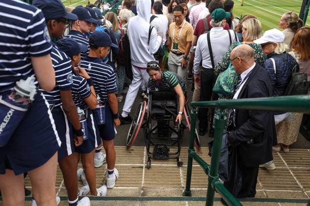 Wimbledon Tag Elf 13. Juli 2023, Wimbledon Wimbledon Tennis Championships Tag Elf Ein Mitarbeiter des Bodenpersonals bringt den Rollstuhl eines Teilnehmers die Treppe hinauf Foto Charlotte Wilson Abseits Wimbledon UK  Copyright: xCharlottexWilsonx xOffsidexOffside