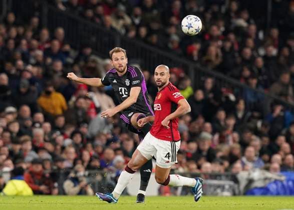 Manchester, England, 12th December 2023. Harry Kane of Bayern Munich clips the ball past Sofyan Amrabat of Manchester United, ManU during the UEFA Champions League match at Old Trafford, Manchester. Picture credit should read: Andrew Yates Sportimage EDITORIAL USE ONLY. No use with unauthorised audio, video, data, fixture lists, club league logos or live services. Online in-match use limited to 120 images, no video emulation. No use in betting, games or single club league player publications. SPI-2800-0016