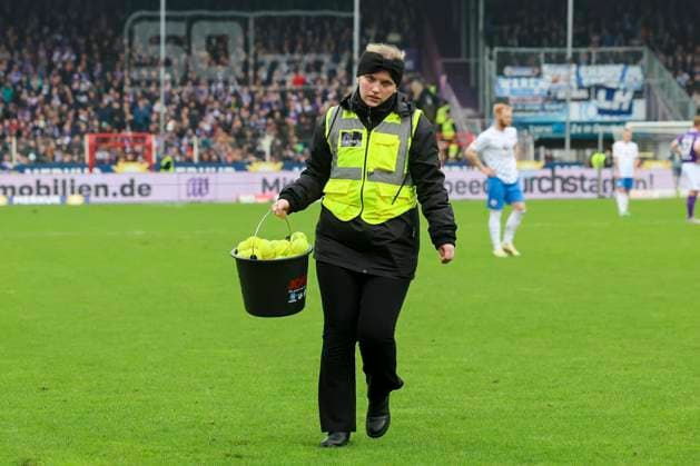 A stewardess runs across the pitch with a bucket full of tennis balls, 2 Bundesliga, VfL Osnabrueck vs Hansa Rostock, Bremer Bruecke, 11 02 2024, Osnabrueck, Germany