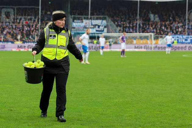 A stewardess runs across the pitch with a bucket full of tennis balls, 2 Bundesliga, VfL Osnabrueck vs Hansa Rostock, Bremer Bruecke, 11 02 2024, Osnabrueck, Germany