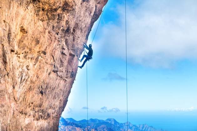 Rock climber climbing up overhanging cliff Rock climber climbing up overhanging cliff with Canary Island mountain range and sea on background (License=RF) 13344631 Copyright: xZoonar.com PavloxVakhrushevx 13344631