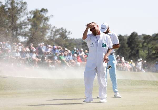 Max Homa and caddie Joe Greiner withstand the gusting wind that blows sand from the bunker across the eighteenth green during the second round of the Masters Tournament at Augusta National Golf Club in Augusta, Georgia on Friday, April 12, 2024. Woods finished the day at one-over-par.  AUG202404121008 JOHNxANGELILLO