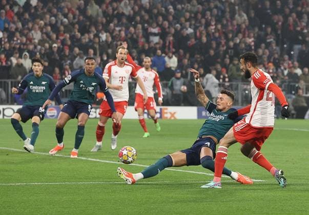 Noussair Mazraoui of Bayern Munich has a shot despite the attentions of Ben White of Arsenal Bayern Munich v Arsenal, UEFA Champions League, Quarter Final, Second Leg, Football, Allianz Arena, Munich, Germany - 17 Apr 2024 EDITORIAL USE ONLY No use with unauthorised audio, video, data, fixture lists, club league logos or live services. Online in-match use limited to 120 images, no video emulation. No use in betting, games or single club league player publications.  Copyright: xMichaelxZemanek Shutterstockx 14434936v