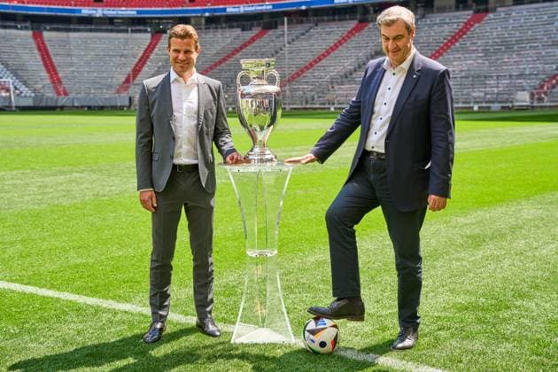 Ministerpräsident Dr. Markus Söder (CSU) zusammen mit FIFA Schiedsrichter Felix Brych auf dem Fußball Spielfeld der Allianz Arena in München, neben dem Henri-Delaunay-Pokal der UEFA EURO 2024