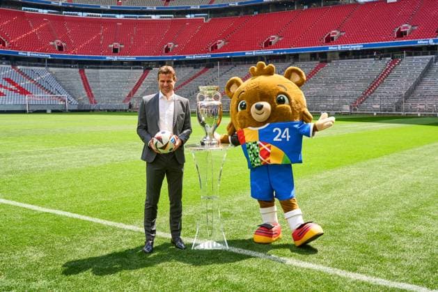 FIFA Schiedsrichter Felix Brych neben dem Henri-Delaunay-Pokal der UEFA EURO 2024 auf dem Fußball Spielfeld der Allianz Arena in München. EM Maskottchen Albärt neben dem Pokal