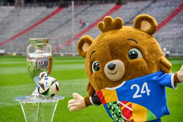 Themenbild Fußball EURO 2024: Maskottchen der Europameisterschaft Albärt steht auf dem Spielfeld der Allianz Arena zusammen mit dem offiziellen Spielball von Adidas und dem Henri-Delaunay-Pokal der UEFA EURO 2024
