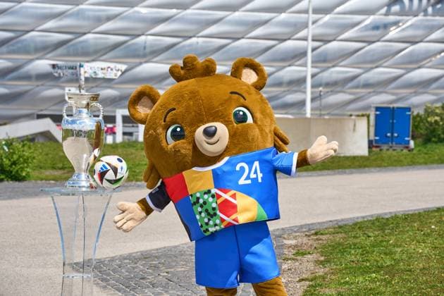 Maskottchen Albärt der Fußball-EM UEFA EURO 2024 mit dem Spielball von Adidas und dem Henri-Delaunay-Pokal vor der Allianz Arena in München