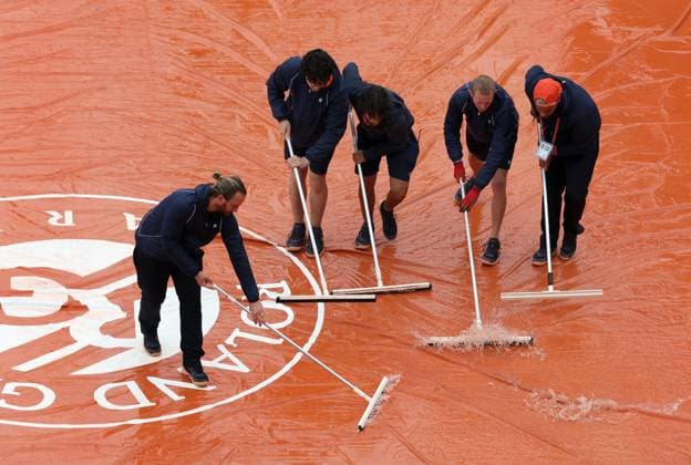 Helpers wipe water off the tarpaulin protecting the clay of a tennis court in a bid to resume a match of the French Tennis Open at Roland Garros in Paris, France, on Saturday, June 1, 2024. Persistent rain and cold temperatures have thrown a wet blanket on the Paris Grand Slam tournament, leaving disgruntled fans starved of action and organisers racing to clear a backlog of matches.  PAR20240601144 MAYAxVIDON-WHITE