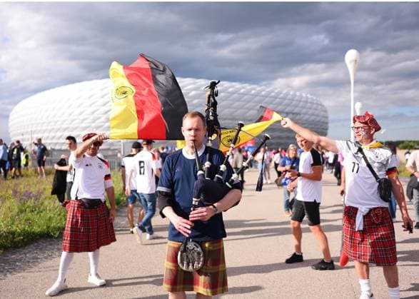 Munich, Germany, 14th June 2024. A piper plays his lament outside the stadium kept company by two kilt wearing German fans during the UEFA European Championships match at Allianz Arena, Munich. Picture credit should read: David Klein Sportimage EDITORIAL USE ONLY. No use with unauthorised audio, video, data, fixture lists, club league logos or live services. Online in-match use limited to 120 images, no video emulation. No use in betting, games or single club league player publications. SPI-3194-0021