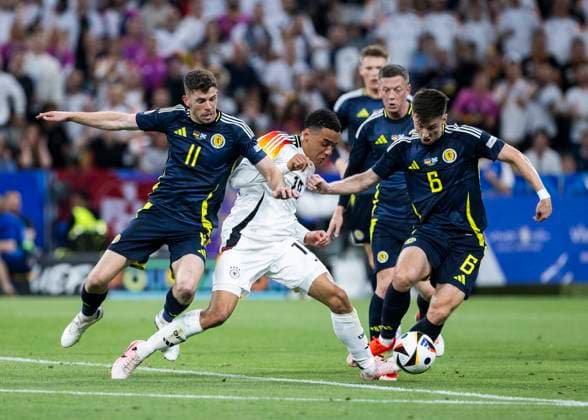 Muenchen, Allianz Arena, 19 09 2021 Jamal Musiala of germany M gets no penalty after this foul from Ryan Christie of scotland L and Kieran Tierney of scotland during the match UEFA European Championship 2024 Germany v Scotland