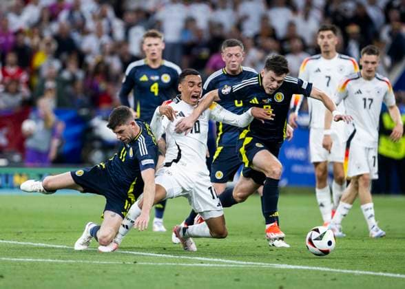 Muenchen, Allianz Arena, 19 09 2021 Jamal Musiala of germany M gets no penalty after this foul from Ryan Christie of scotland L and Kieran Tierney of scotland during the match UEFA European Championship 2024 Germany v Scotland