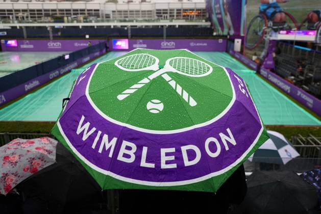 15th June 2024; Cinch Championships, Queens Club, West Kensington, London, England: Cinch Championships Queens Club, Qualifying Day 1; A spectator stays dry under a Wimbledon Championships umbrella while Court 1 is covered during a rain delay  ActionPlus12654642 JohnxPatrickxFletcher