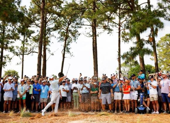 Spectators watch as Rory McElroy of Northern Ireland hits his approach shot from the rough to the 14th hole in the final round of the 124th U.S. Open golf championship at Pinehurst Resort & Country Club in Pinehurst, N.C. on Sunday, June 16, 2024. DeChambeau won with a six-under-par score of 27.  NCP20240616910 JOHNxANGELILLO