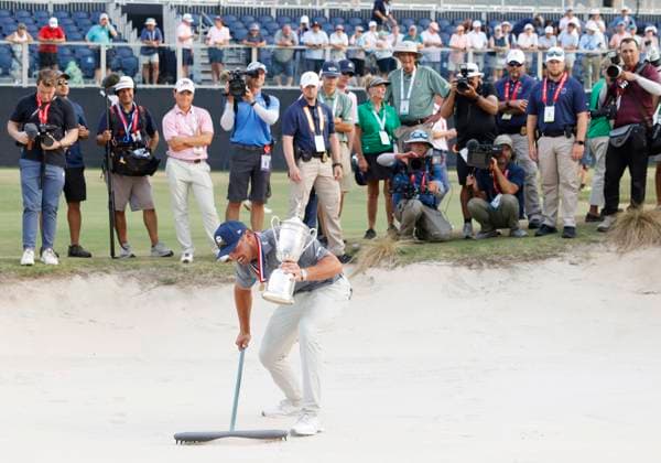 Sport Bilder des Tages Bryson DeChambeau rakes a bunker holding the championship trophy after winning the 124th U.S. Open golf championship at Pinehurst Resort & Country Club in Pinehurst, N.C. on Sunday, June 16, 2024. DeChambeau won with a six-under-par score of 27.  NCP20240616916 JOHNxANGELILLO