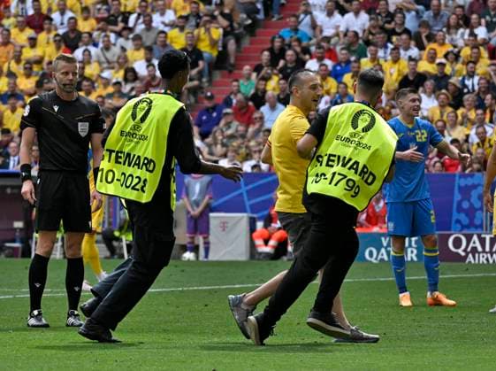 17 06 2024, Football UEFA EURO 2024, preliminary round, match 10, Romania Ukraine, in the Munich Football Arena A streaker is led off the pitch by two stewards
