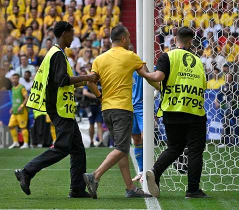 17 06 2024, Football UEFA EURO 2024, preliminary round, match 10, Romania Ukraine, in the Munich Football Arena A streaker is led off the pitch by two stewards