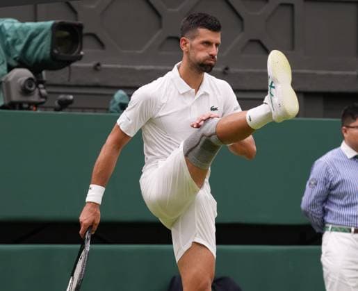 Lawn Tennis - 2024 Wimbledon Championship - Vic Kopriva (CZE) v Novak Djokovic (SRB) - All England Lawn Tennis & Croquet Club - Tuesday 2nd July 2024 Novak Djokovic (SRB) stretches his leg with his knee support 