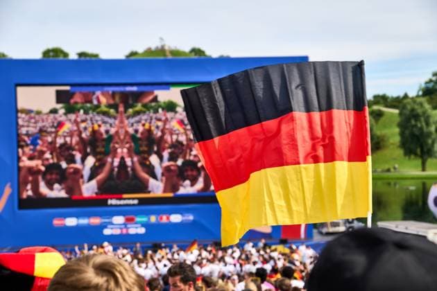 Public Viewing in der Fanzone in München im Olympiapark beim Viertelfinale der UEFA EURO 2024 Deutschland gegen Spanien. Fan Deutschland Flagge vor dem großen Bildschirm in der Fanmeile
