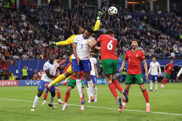 Hamburg, Germany, 5th July 2024. Mike Maignan of France punches clear from Joao Palhinha of Portugal and Jules Kounde of France during the UEFA European Championships quarter final match at Volksparkstadion, Hamburg. Picture credit should read: Jonathan Moscrop Sportimage EDITORIAL USE ONLY. No use with unauthorised audio, video, data, fixture lists, club league logos or live services. Online in-match use limited to 120 images, no video emulation. No use in betting, games or single club league player publications. SPI-3219-0016