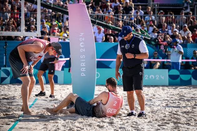 01 08 2024, Paris, Eiffel Tower Stadium Beach volleyball, Olympic Games, preliminary round Clemens Wickler GER trips over net camera and injures himself Nils Ehlers GER and referee Giovanni Bake RSA with him