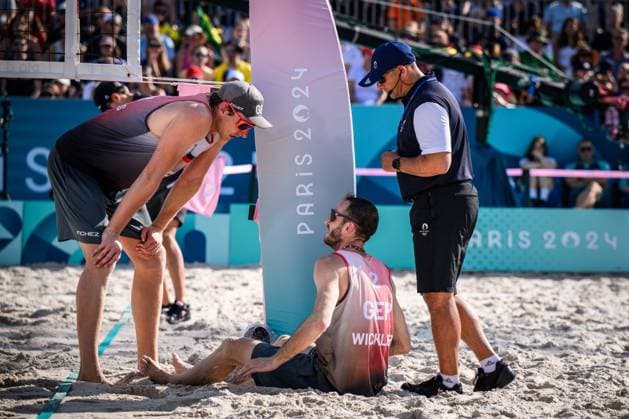 01 08 2024, Paris, Eiffel Tower Stadium Beach volleyball, Olympic Games, preliminary round Clemens Wickler GER trips over net camera and injures himself Nils Ehlers GER and referee Giovanni Bake RSA with him