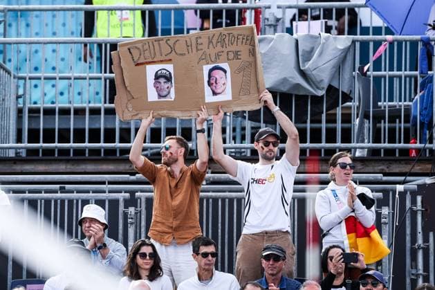 FRA, Paris, Olympic Games Paris 2024, 03 08 2024, Beach Volleyball Mens Round of 16, Eiffel Tower Centre Court Nils Ehlers Germany, 1 and Clemens Wickler Germany, 2 against George Souto Maior Wanderley Brazil, 1 and Andre Loyola Stein Brazil, 2 Fans with poster German potatoes on the 1 Copyright: HMBxMedia SteffiexWunderl