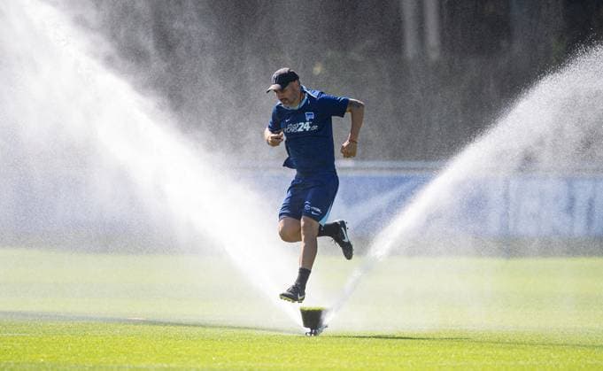 Soccer, Men, Season 2024 25, 2 Bundesliga, Hertha BSC, Training, Coach Cristian Fiel Hertha BSC jumps over a sprinkler, 13 08 2024, Copyright: xSebastianxRäppold MatthiasxKochx