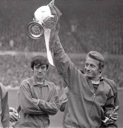 Football - 1966 1967 First Division - Manchester United, ManU 0 Stoke City 0 United co-club captain Denis Law holds aloft the league championship trophy, with teammate George Best, behind, at Old Trafford. 